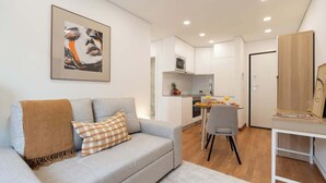 Un espace de vie moderne avec un canapé gris, une œuvre d’art encadrée et une table à manger avec des chaises.