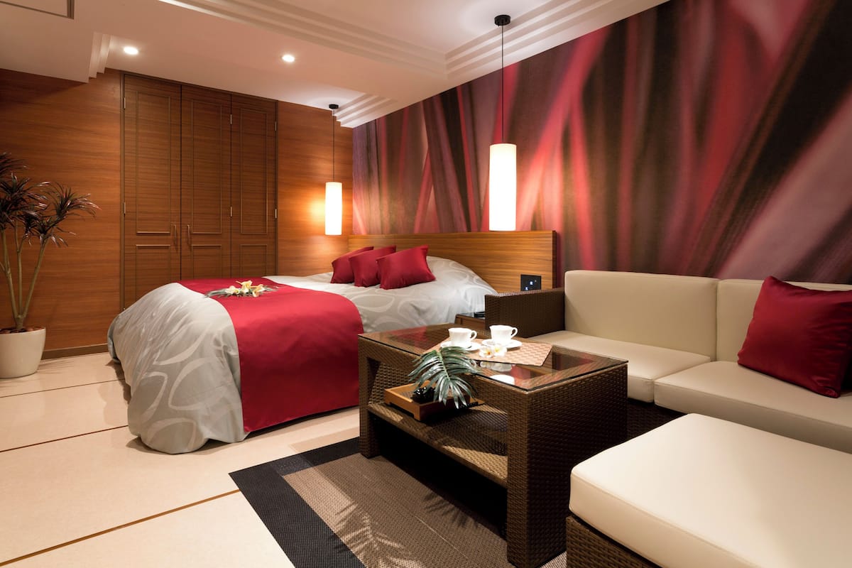 A hotel room with a large bed, a sofa, a coffee table, and a wardrobe.