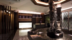 Un vestíbulo moderno con mostrador de recepción, zona de estar e iluminación decorativa.
