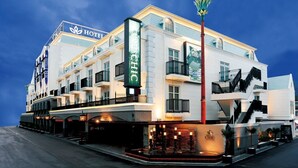 Un hotel de varios pisos con un llamativo letrero 'HOTEL CHIC', una fachada moderna y una entrada bien iluminada.