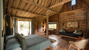 A rustic wooden cabin with a large bed, a sofa, and a dining area. - Desa Seni  (Baturiti)