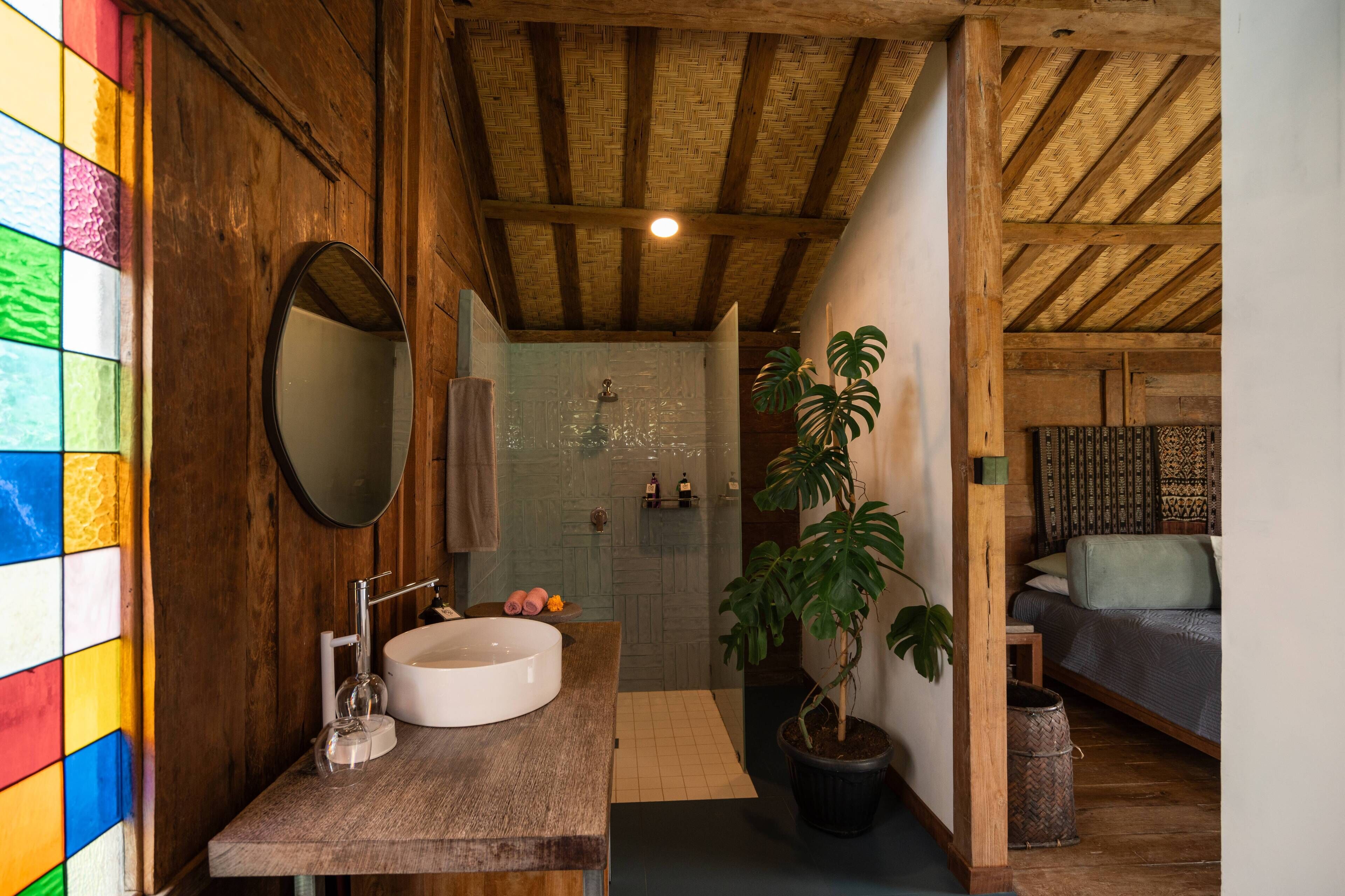 A rustic bathroom with a wooden vanity, a large mirror, and a shower area.