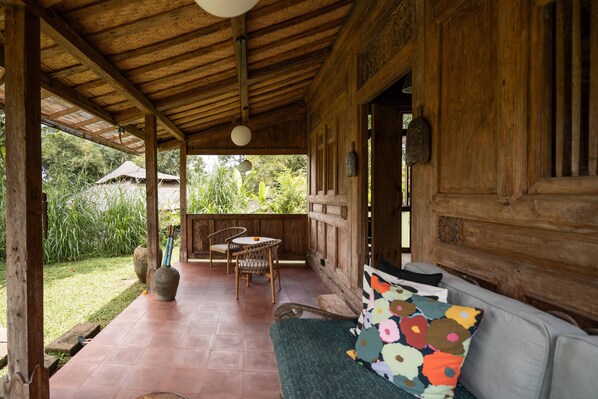 Eine hölzerne Veranda mit einer gepolsterten Bank, einem Tisch und Stühlen.