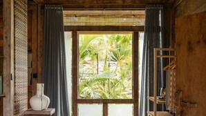 A rustic wooden room with a large window, a hanging light fixture, and a shelf with a vase. - Desa Seni  (Baturiti)