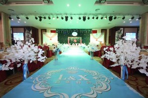 A hotel reception area with a blue carpet, reception desk, and a green backdrop. - Tianlu Hotel (Shangnan)