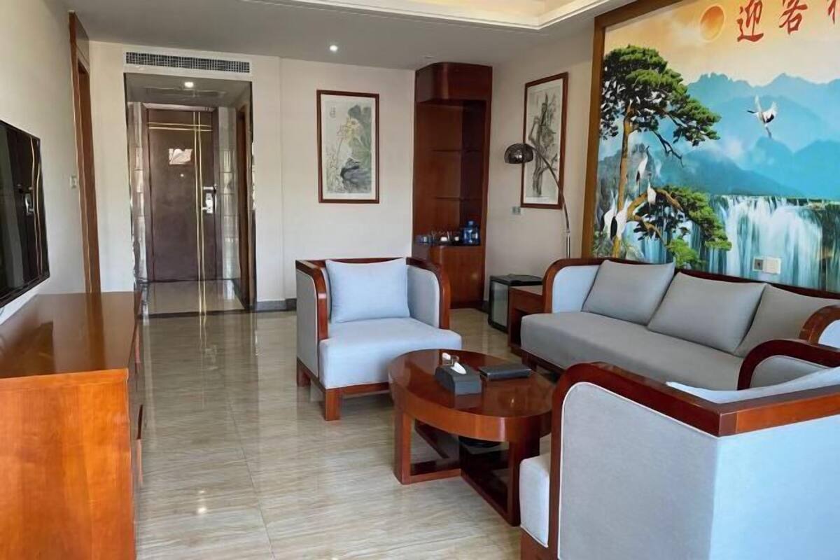 A hotel lobby with a sofa set, a coffee table, a TV, and artwork on the walls.