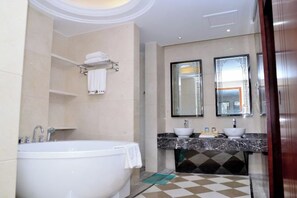 Un baño moderno con bañera, dos lavamanos y un espejo grande.