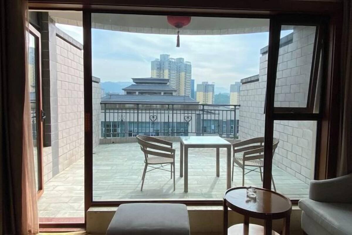 A room with a large window, a small table, a bench, and a chair.