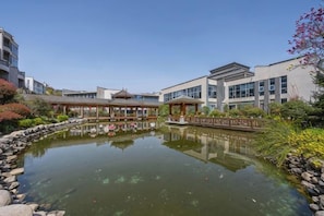 A courtyard with a pond, traditional-style buildings, and modern architecture.