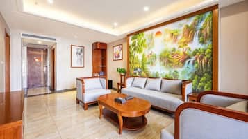 A hotel lobby with a large painting, a sofa, a coffee table, and a reception desk.