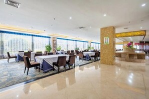 Un salón de conferencias con mesas y sillas, una recepción y un pilar decorativo.