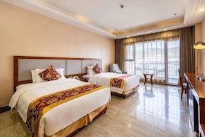 Una habitación de hotel con dos camas, un escritorio y un balcón.