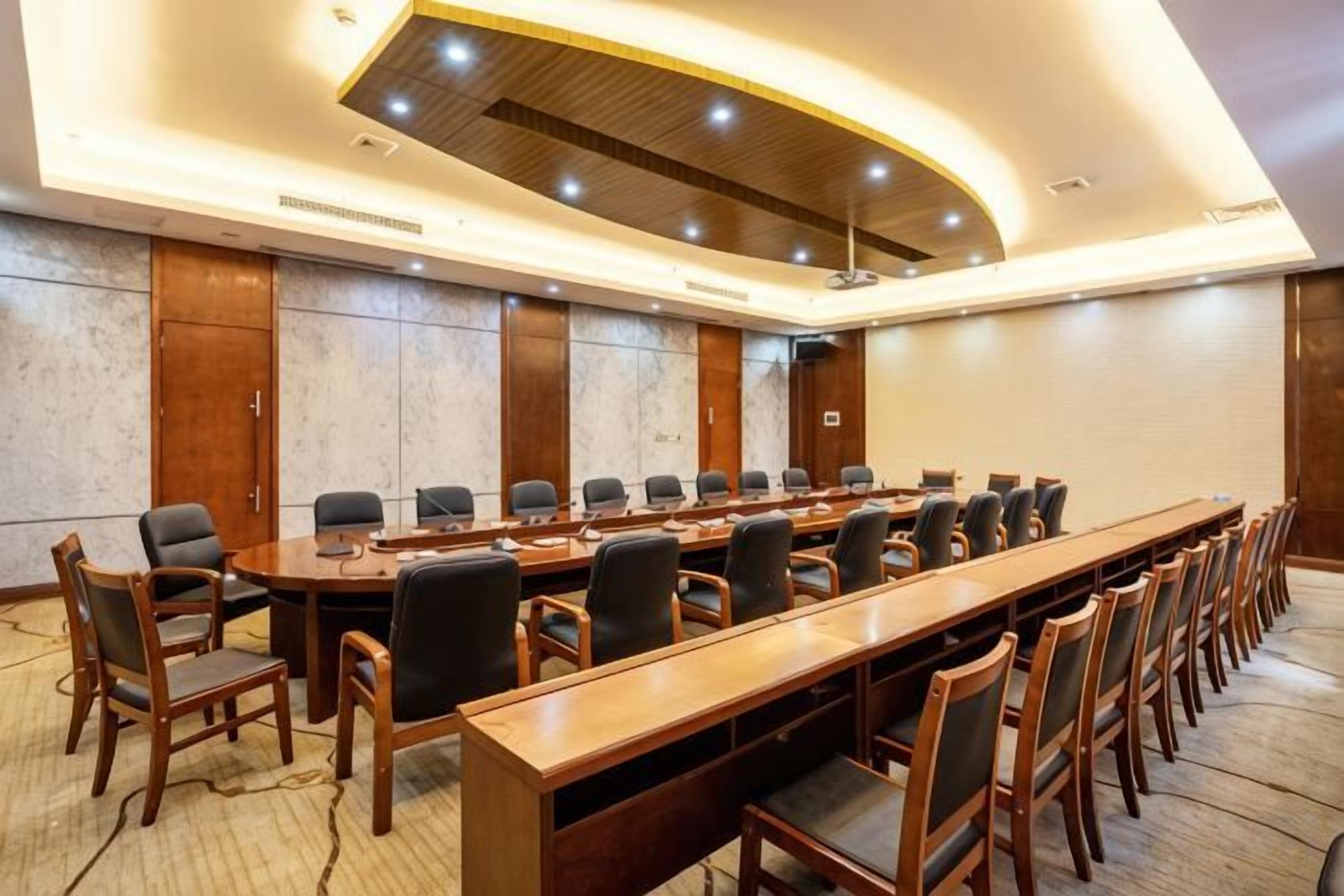 A conference room with a long table, multiple chairs, and a modern ceiling design.
