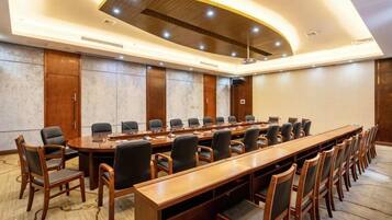 A conference room with a long table, multiple chairs, and a modern ceiling design.