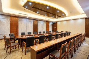 Un salón de conferencias con una larga mesa, varias sillas y un diseño moderno en el techo.