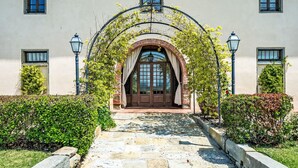 A building with a central arched entrance, stone pathway, and symmetrical windows.