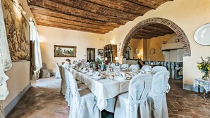A dining area with a brick ceiling, white tablecloths, and chairs.