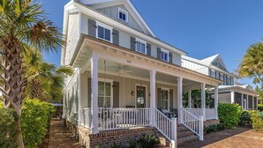 A two-story house with a covered porch and a brick pathway. - 66 Palmetto Lane located in Ocean Oaks on Jekyll (Jekyll Island)