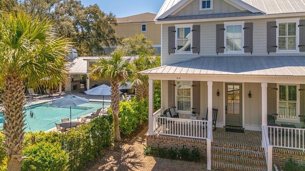 A two-story house with a covered porch and a swimming pool. - 66 Palmetto Lane located in Ocean Oaks on Jekyll (Jekyll Island)