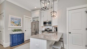 A modern kitchen with white cabinetry, stainless steel appliances, and a central island. - 66 Palmetto Lane located in Ocean Oaks on Jekyll (Jekyll Island)