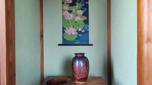Ein Holztisch mit einer Vase und einem gerahmten Kunstwerk von Lotusblumen an der Wand.