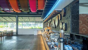 Un área de bufé con diversas opciones de comida, una estación de café y una zona de estar con sillas.