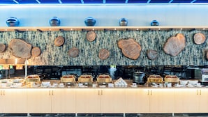 Un área de bufé con un diseño de pared de madera, varias estaciones de servicio y una variedad de recipientes para alimentos.