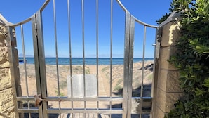 A metal gate with a view of the beach and ocean through the gaps. - Duplex apartament Bahia Azul on the beachfront for 4 persons (Dénia)