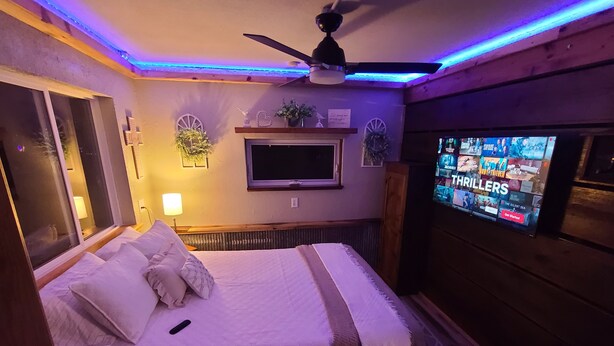 Une chambre à coucher avec un lit, un téléviseur et un ventilateur de plafond.