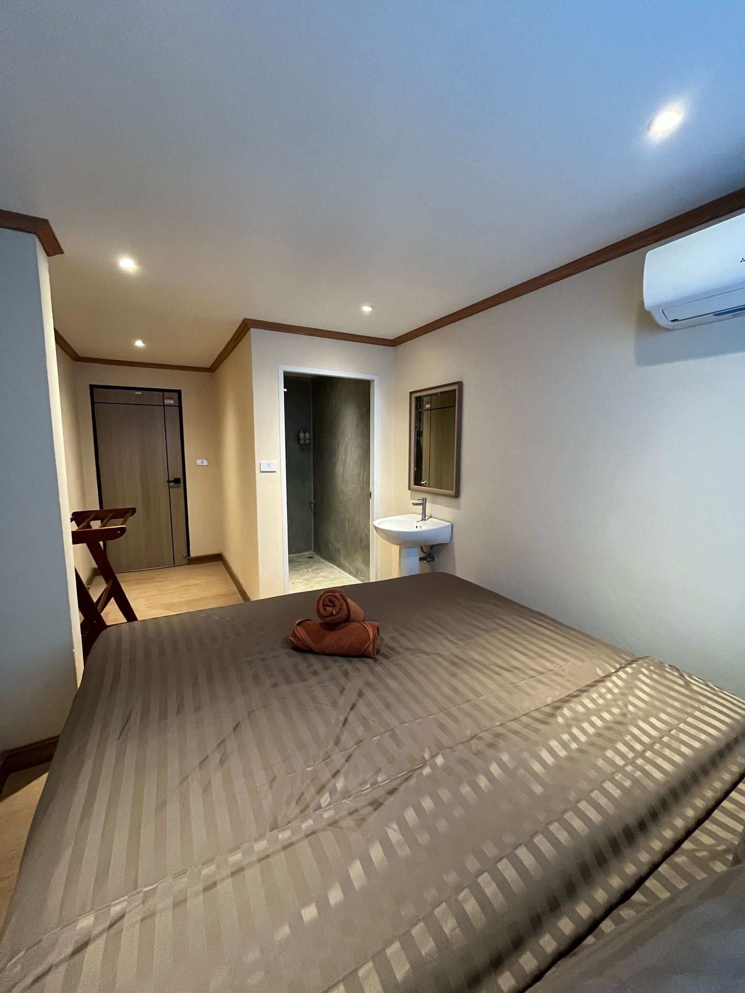 Una habitación de hotel con cama, baño con lavamanos y ducha.