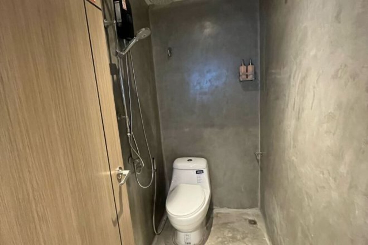 Une petite salle de bain compacte, avec des toilettes blanches, une douche et une porte en bois.