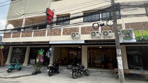 Un edificio a due piani con diversi condizionatori d'aria, una motocicletta parcheggiata davanti e un negozio con insegna al neon.