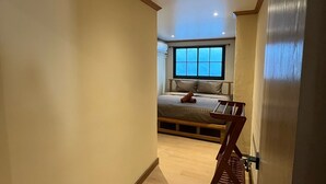 Un corridoio stretto che conduce a una camera da letto con un letto, una finestra e una sedia di legno.