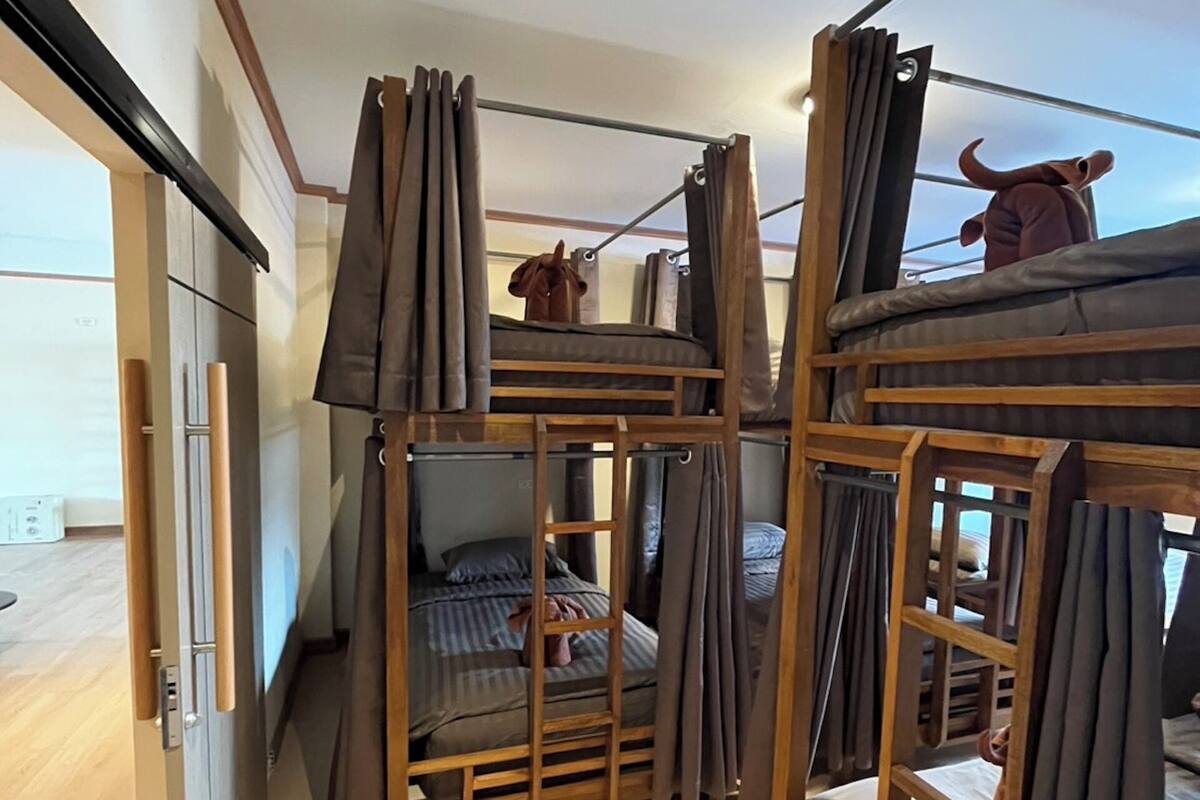 Ein kleines Zimmer mit Etagenbetten, Holzrahmen und Vorhängen.