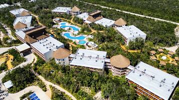 An aerial view of a resort with multiple buildings, swimming pools, and a parking area.