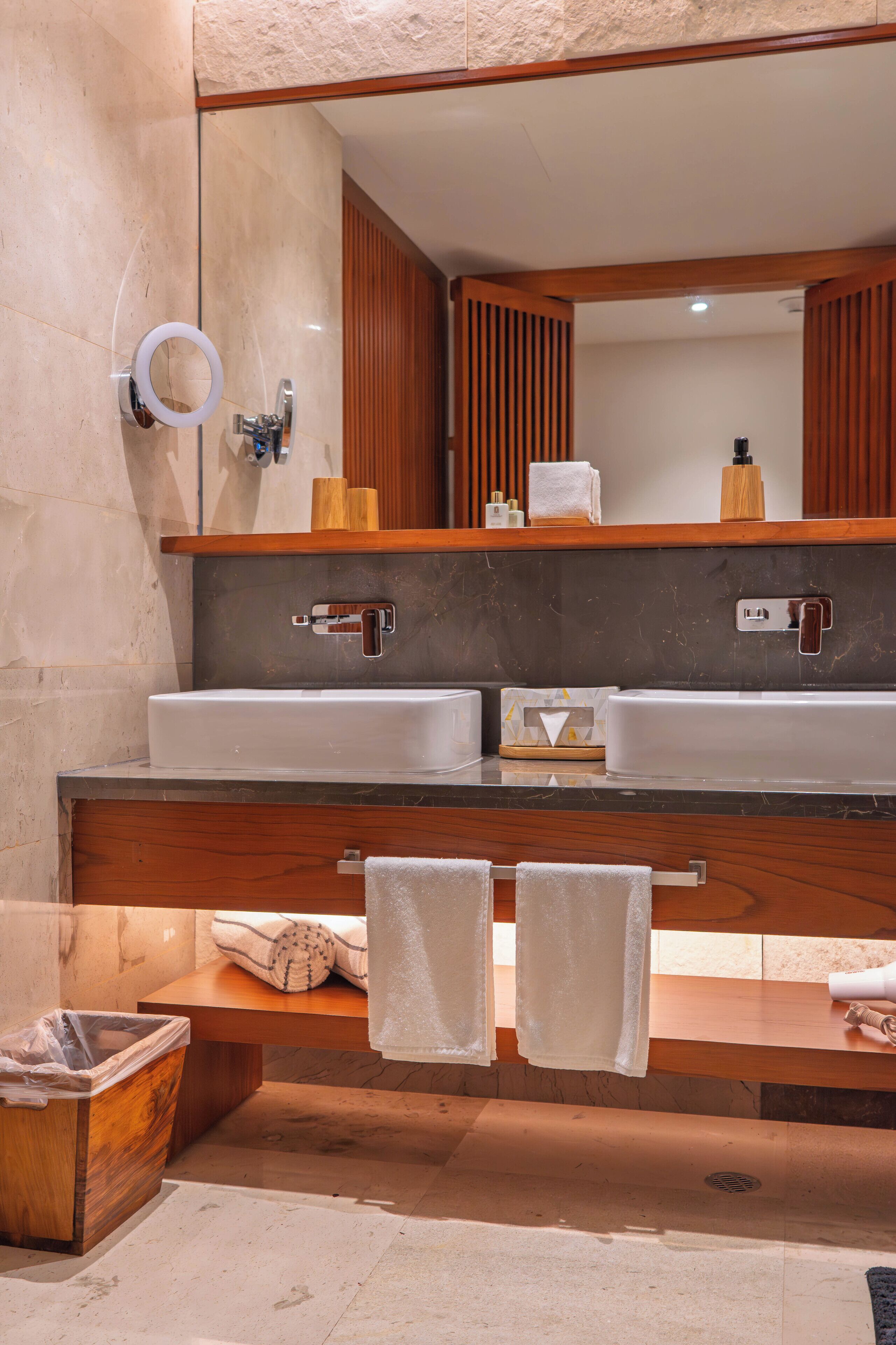 Un baño moderno con dos lavamanos, tocador de madera y un espejo grande.