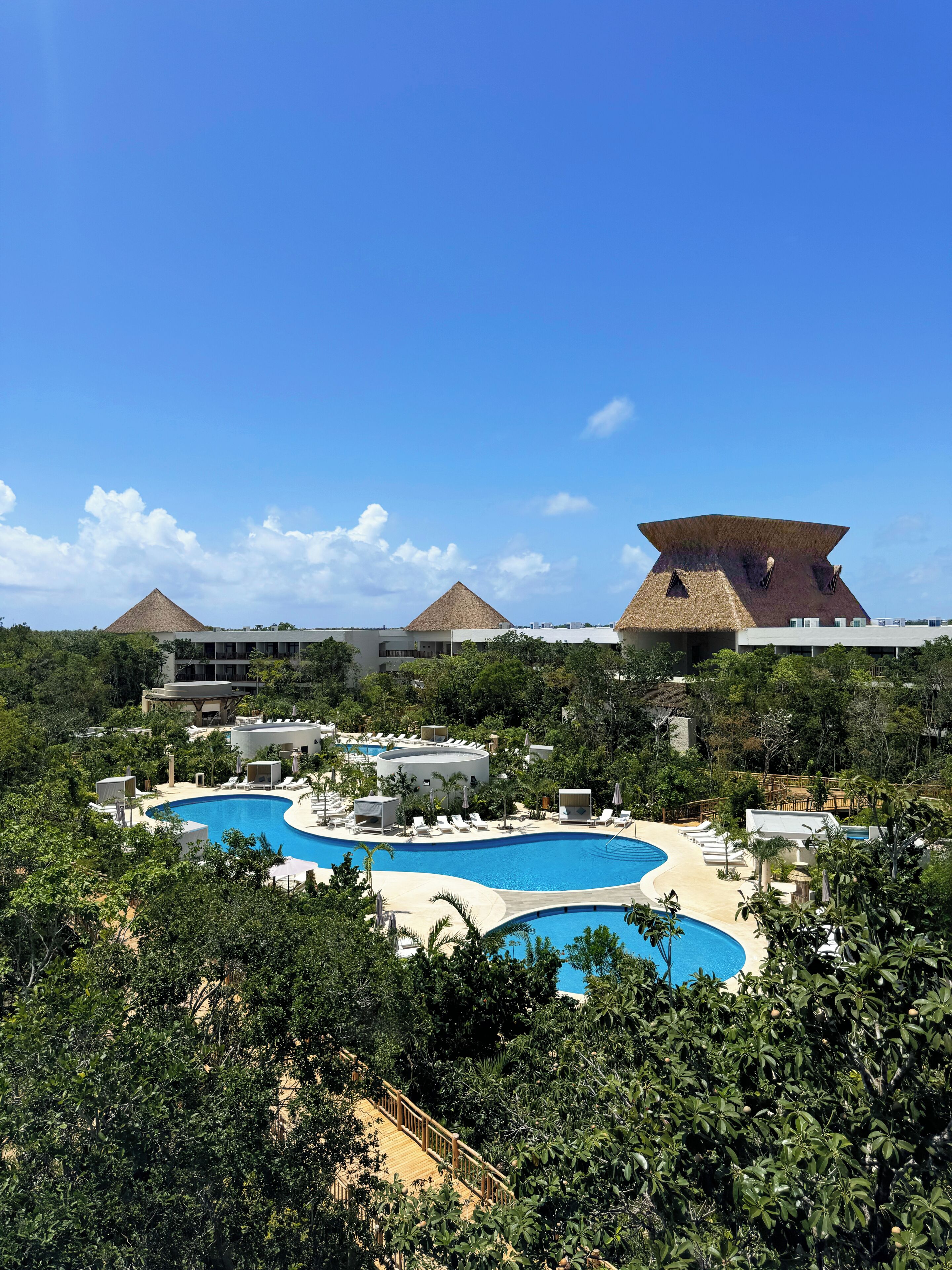 Un resort con diverse piscine, verde lussureggiante e architettura moderna.