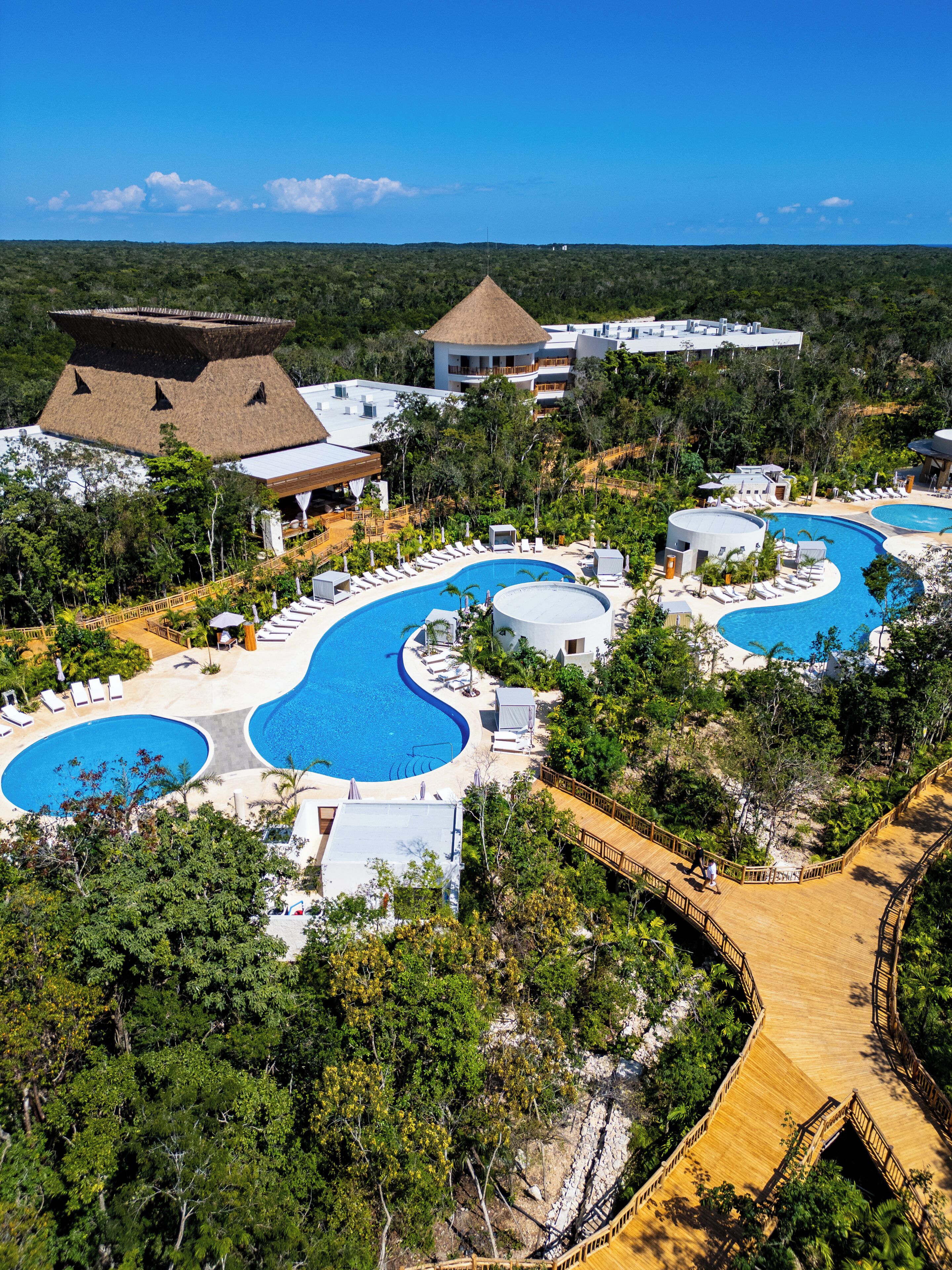 A resort with multiple swimming pools, a wooden deck, and lush greenery.