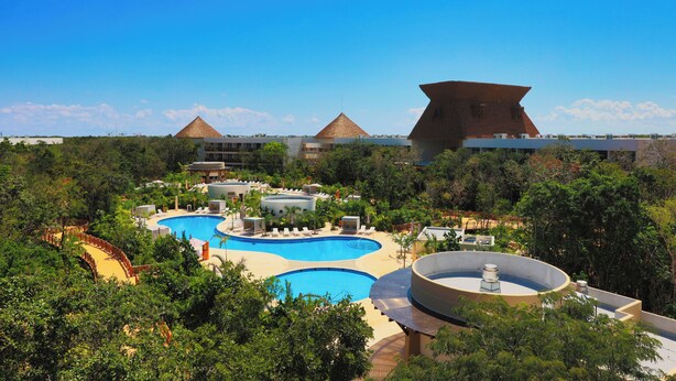 A resort with multiple swimming pools, a large central pool, and a distinctive pyramid-shaped building in the background. - Hotel Mundo Maya Tulum (Tulum)