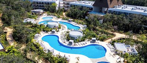 Un resort con varias piscinas, zonas de descanso y un entorno boscoso.