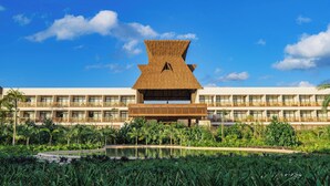 A hotel with a distinctive thatched roof structure, multiple balconies, and lush greenery surrounding a central pool. - Hotel Mundo Maya Tulum (Tulum)