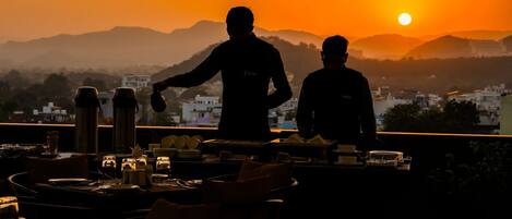 Ein Restaurant mit Blick auf den Sonnenuntergang und die Berge.