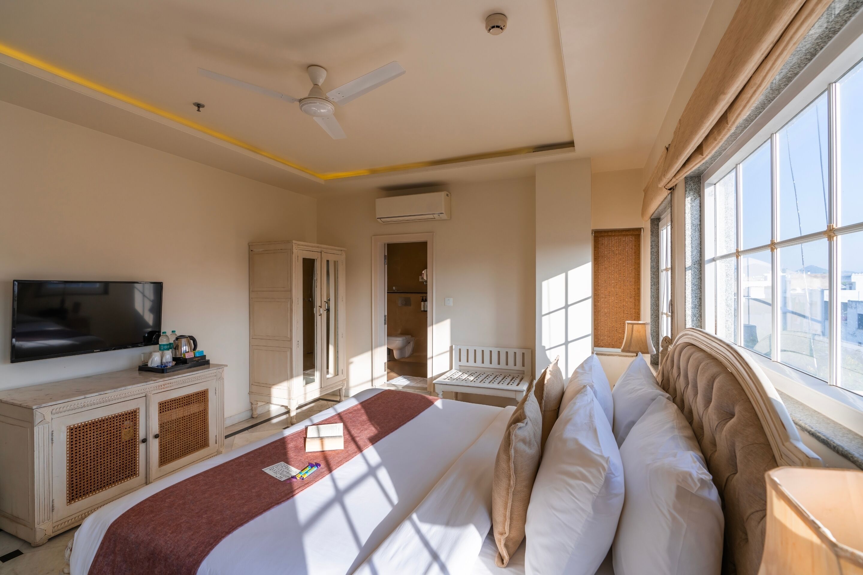 Une chambre d’hôtel équipée d’un lit, d’une télévision, d’une armoire et d’une fenêtre donnant sur un paysage agréable.
