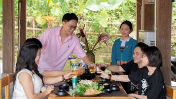 A group of people toasting at a wooden table with a tropical garden view.