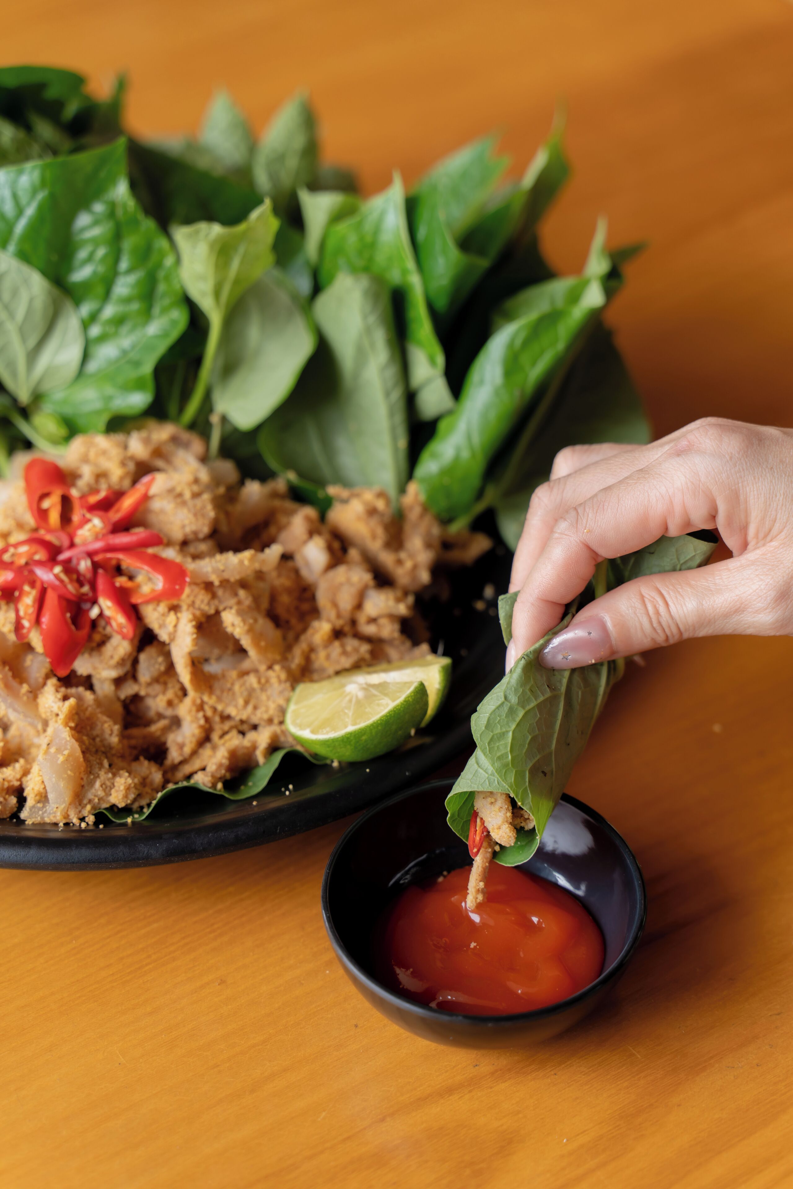 A plate of food with a lime wedge and a small bowl of sauce.
