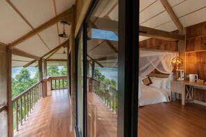 Une chambre avec une grande fenêtre, un plancher en bois, un lit avec une literie blanche, une table de chevet avec une lampe, et une vue sur un lac.