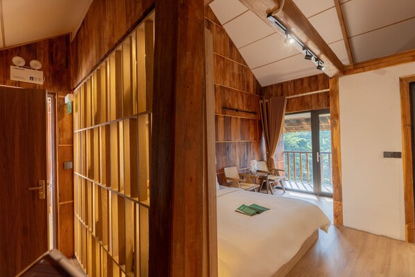 Una habitación de madera con una cama, un escritorio y un balcón.