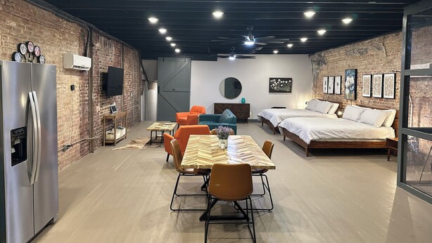 A modern, well-lit room with a brick wall, a large bed, a dining table with chairs, and a refrigerator. - Livie’s Loft
Trendy loft on Main Street (Sardis)