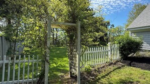 A garden with a wooden pergola, a white picket fence, and a lawn. - Orleans Beach Retreat (Orleans)