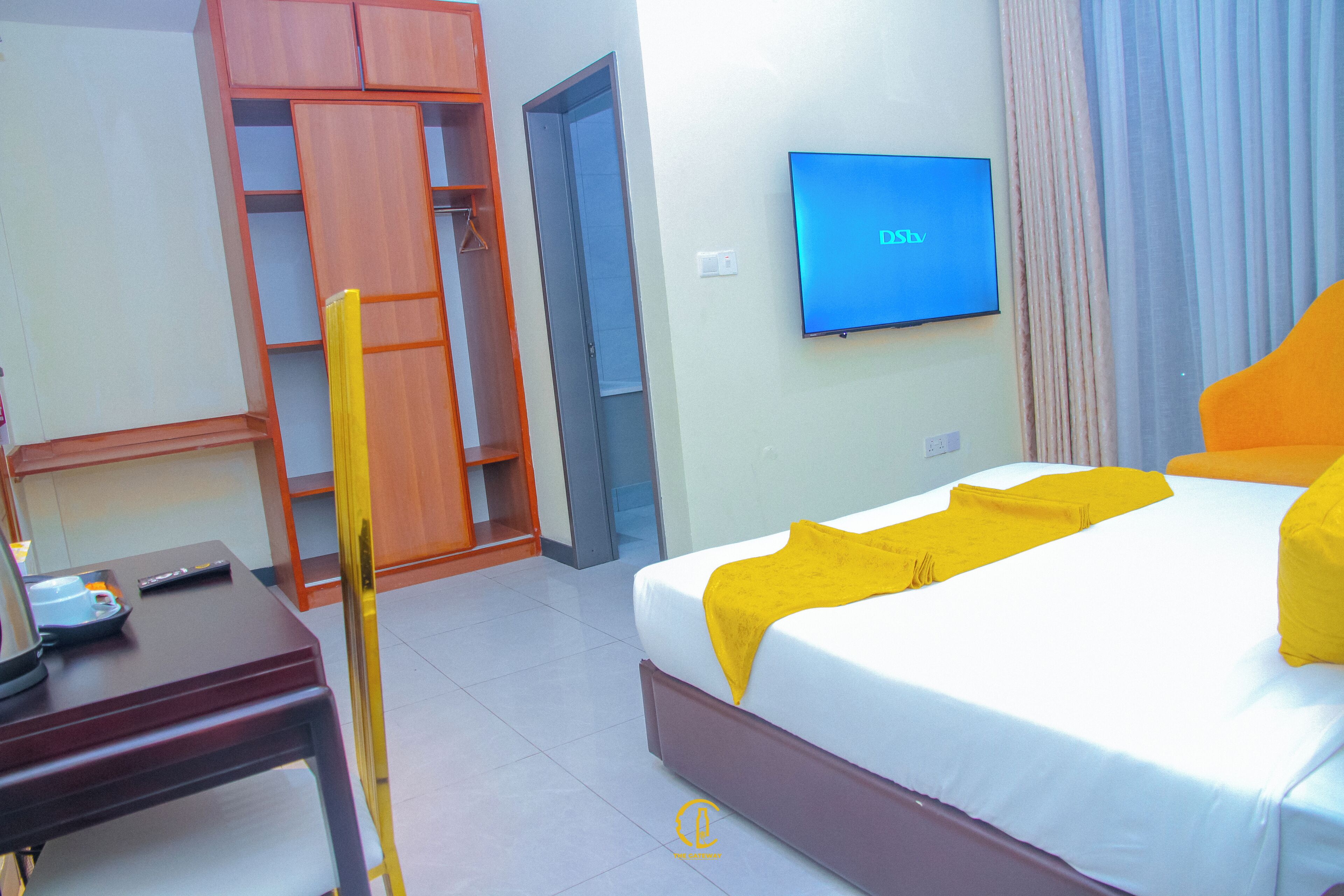 Una camera d'albergo con un letto, una TV, una scrivania e un armadio.